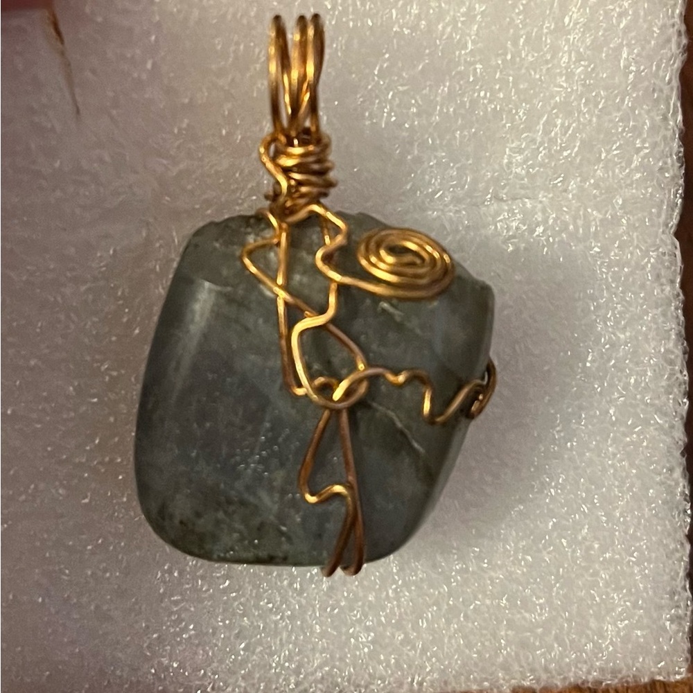 Aquamarine pendant with gold wire surround.